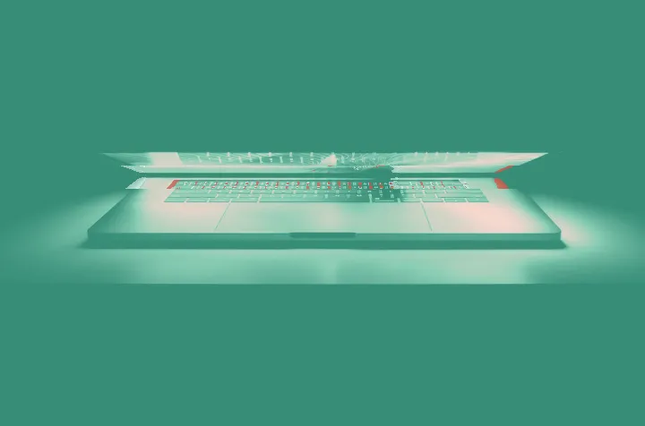 Barely open laptop glowing orange and purple against a black background